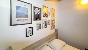 A bedroom with a wooden headboard, a bed with white linens, and a wall adorned with framed artwork including a nature scene and abstract pieces. - La Maison Pilly - Valtellina (Sondalo)