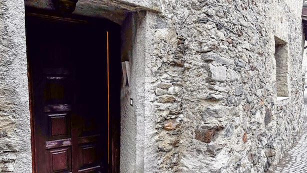 A stone building with a wooden door and a cobblestone path. - La Maison Pilly - Valtellina (Sondalo)