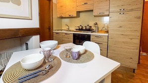 A modern kitchen with wooden cabinets, a white countertop, and a dining table set with bowls and cups. - La Maison Pilly - Valtellina (Sondalo)