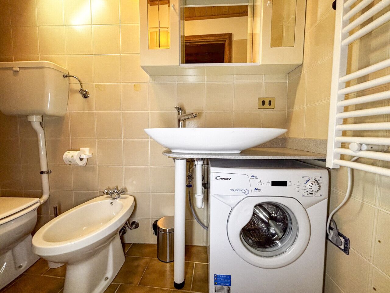 Un baño con bidé, lavabo y lavadora.