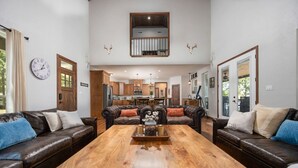 Amplia sala de estar con sofás de cuero, una mesa de centro de madera y una cocina al fondo.