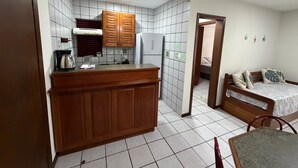 A compact kitchen with wooden cabinets, a refrigerator, and a coffee maker. - Viva Canasvieiras Apartment 50m from the beach (Florianópolis)