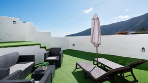 Une terrasse sur le toit, avec un revêtement de gazon synthétique, du mobilier d’extérieur et une vue sur les montagnes.