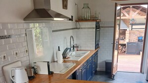 Eine moderne Küche mit Holzarbeitsplatte, weißen Barhocker und Blick auf einen Außenbereich.