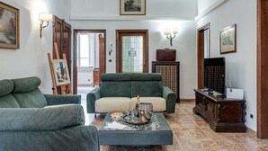 A living room with two green sofas, a coffee table with a bottle and glasses, and a TV stand with a television. - Beautiful and spacious modern apartment in Florence, located in the quiet and well-connected Campo di Marte area. Situated on the first floor, the apartment can accommodate up to 7 guests with 2 double beds and 3 single bed, arranged across 4 bedrooms. I (Firenze)