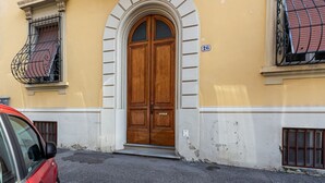 A yellow building with a large wooden double door, a small window with a metal grill, and a number '26' on the wall. - Beautiful and spacious modern apartment in Florence, located in the quiet and well-connected Campo di Marte area. Situated on the first floor, the apartment can accommodate up to 7 guests with 2 double beds and 3 single bed, arranged across 4 bedrooms. I (Firenze)