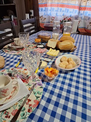 Une table de petit-déjeuner avec divers aliments, une nappe à carreaux et un décor de cuisine en arrière-plan.