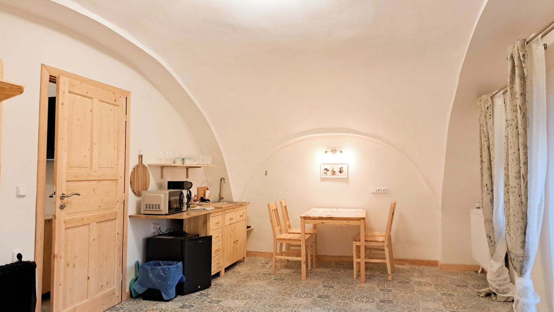 A compact kitchen with wooden cabinets, a microwave, and a small dining table with chairs.