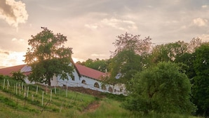 Un bâtiment blanc avec un toit rouge, entouré de verdure et d’arbres.