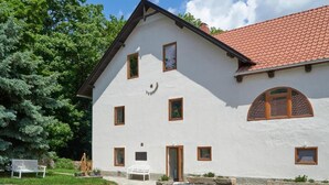 Un bâtiment blanc avec un toit recouvert de tuiles rouges, de nombreuses fenêtres et un banc au premier plan.