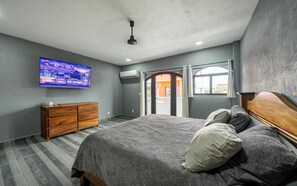 A bedroom with a bed, a TV, a wooden dresser, and a view through an open door. - 2 bedroom apartment with modern and elegant design (Barra de Navidad)