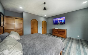 A bedroom with a bed, two wooden doors, a TV on the wall, and a wooden dresser. - 2 bedroom apartment with modern and elegant design (Barra de Navidad)