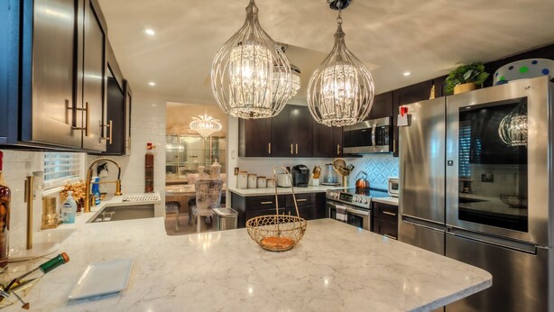 A modern kitchen with a marble countertop, stainless steel appliances, and a central island with a woven basket. - Ocala - WEC. (Ocala)