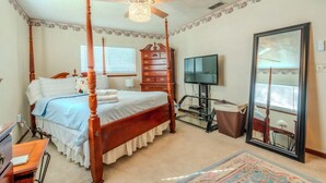 A four-poster bed with a ceiling fan, a dresser, a television, and a mirror in a bedroom. - Ocala - WEC. (Ocala)