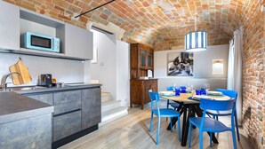 A kitchen with a brick ceiling, a microwave, a sink, and a dining area with blue chairs. - Hostdomus - The Court (Alba)