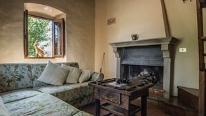 Uma sala de estar acolhedora com sofá, lareira e janela com vista para árvores.