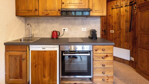 Een koelkast, een oven, kookgerei, borden en bestek