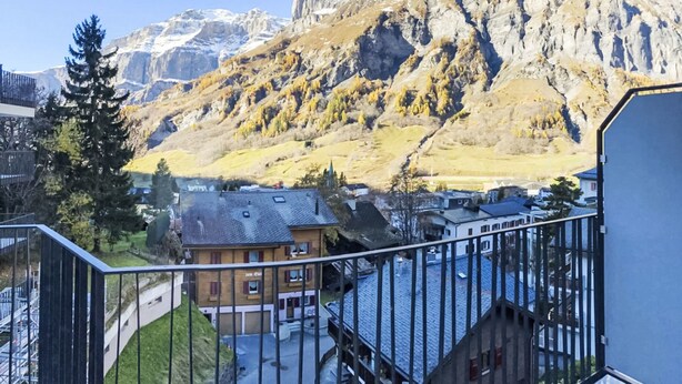 En balkon med udsigt til et bjerg og en bygning med skråtag.