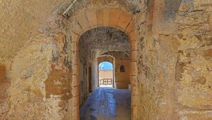 Ein gewölbter Steinkorridor mit Blick auf einen Innenhof am Ende.