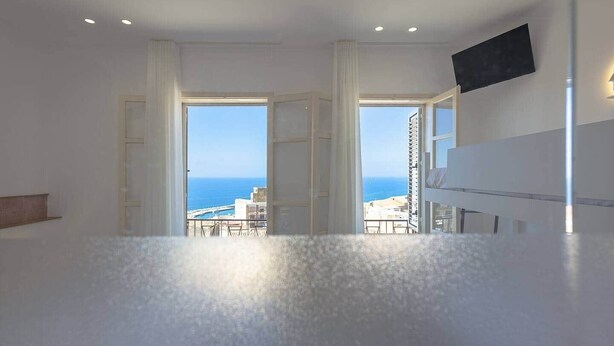 Ein geräumiges Zimmer mit großem Fenster und Meer- und Stadtblick.