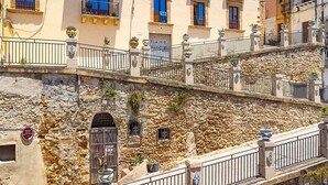 A multi-story building with balconies, stone walls, and potted plants. - Room Castel Perollo - Camera Verde by Biddizzi Rari - Historic Center in Sciacca (Sciacca)