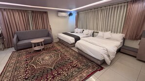 Una habitación de hotel moderna con un sofá, una cama, una mesita y un tapete decorativo.