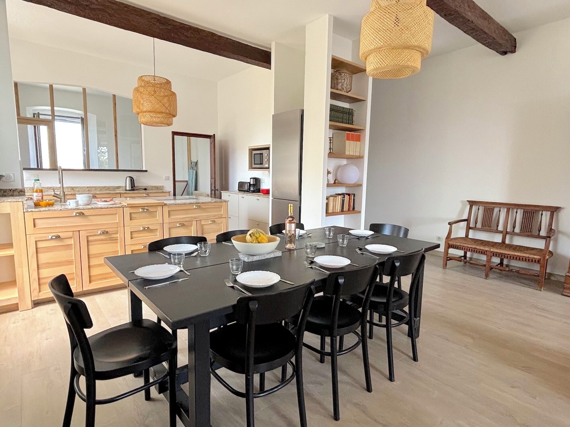 Una cucina moderna con mobili in legno, un tavolo da pranzo per sei persone e una panca in legno nell'angolo.