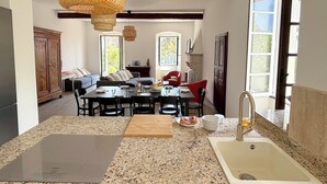 Een ruime keuken met granieten aanrecht, een eethoek met tafel en stoelen, een rode stoel, en een groot raam.