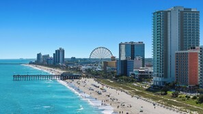 A coastal cityscape with a beach, a large Ferris wheel, and high-rise buildings. - Refreshed & Modern Studio w/ 1 Queen Bed • Steps to Beach & Boardwalk (Myrtle Beach)