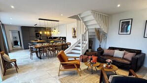 Een ruime woonkamer met een trap, een eethoek en een keuken.