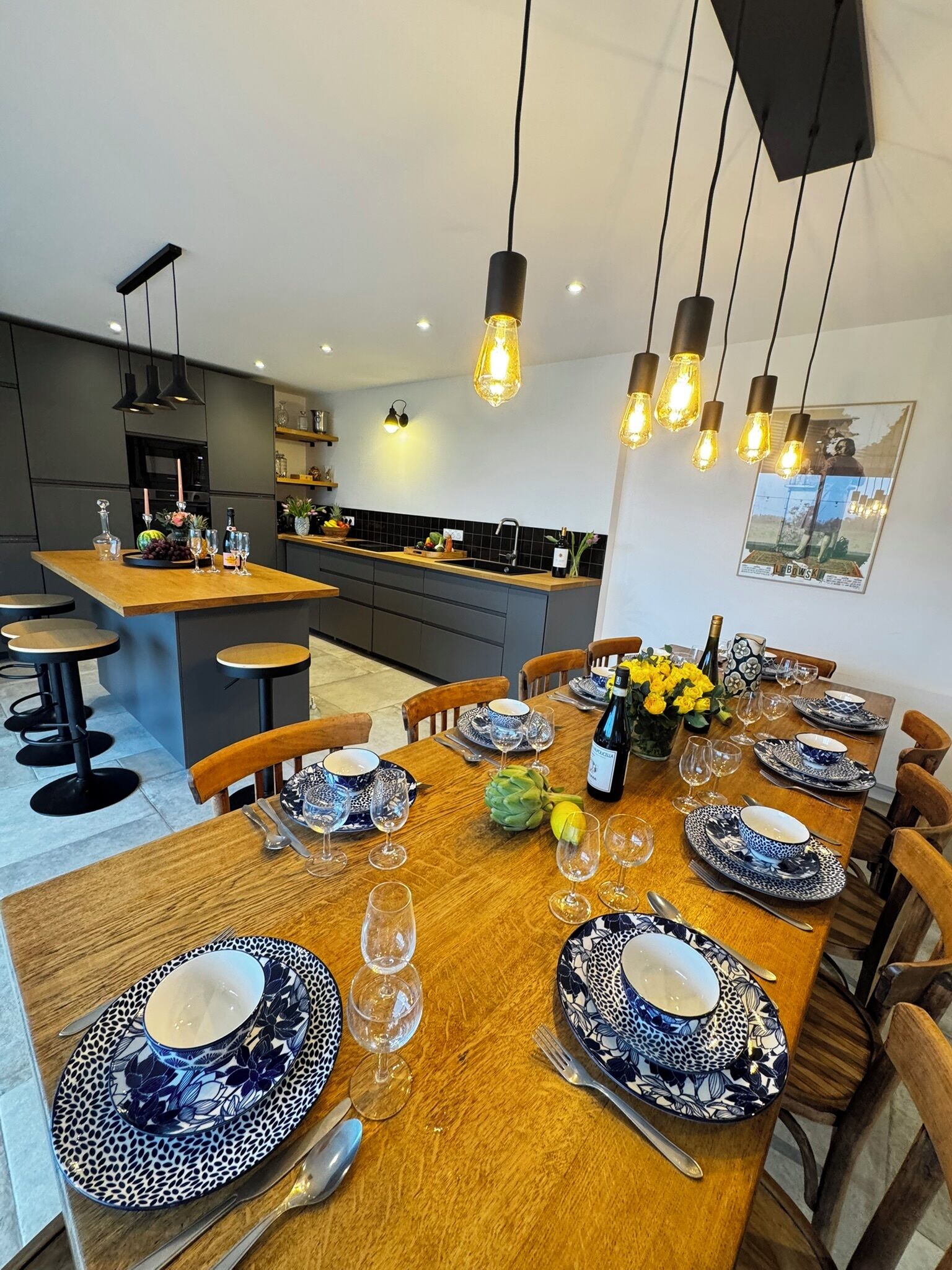A modern kitchen with a central island, dark cabinetry, and pendant lighting.