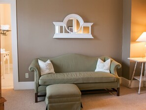 A room with a green sofa, a white side table, and a wall-mounted decorative piece.