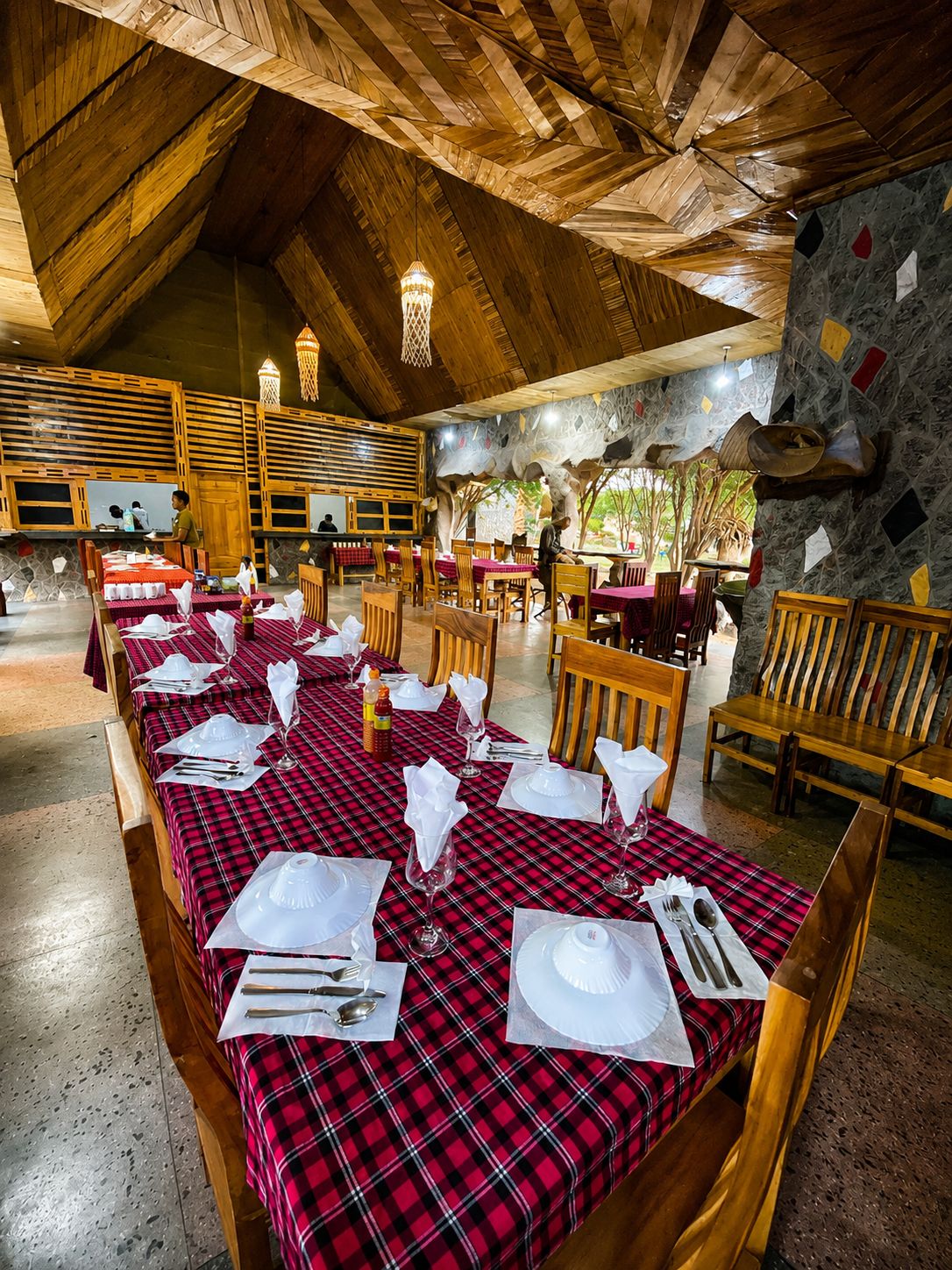 Un restaurant avec des poutres en bois au plafond, des nappes à carreaux rouges et noirs, et des murs en pierre.