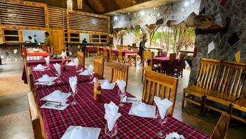 Un restaurante con vigas de madera en el techo, manteles a cuadros rojos y negros y paredes de piedra.