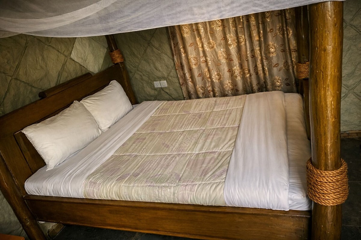 Una cama con dosel, cabecera de madera y cortina con estampado floral.