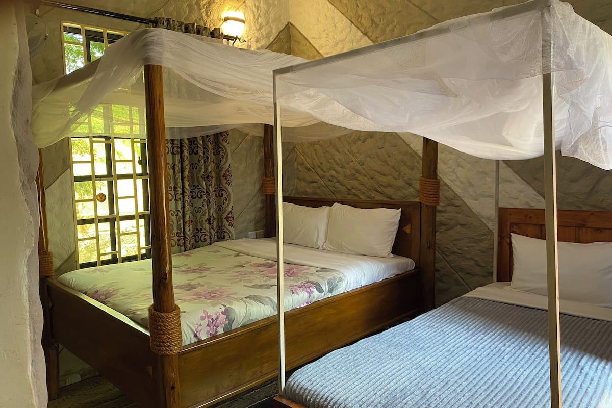Una cama con dosel, una cama más pequeña y una ventana con cortinas.