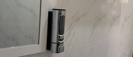 Un baño con pared de mármol, inodoro y zona de ducha.