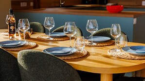 Une table à manger dressée avec des assiettes, des verres et une bouteille, entourée de chaises.