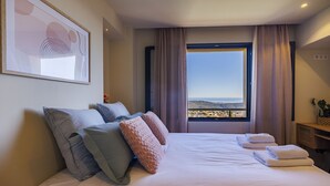 Une chambre d’hôtel avec un grand lit, une vue sur le paysage et une œuvre d’art encadrée au mur.