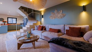 Un salon moderne avec un canapé, une table basse et un escalier menant à un niveau supérieur.