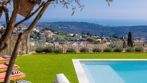 Une piscine avec vue sur une ville, une clôture en bois et un arbre au premier plan.