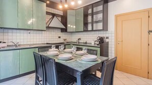A modern kitchen with green cabinets, a dining table set for four, and a wooden door.