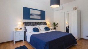 A neatly arranged bedroom with a bed, bedside tables, a wardrobe, and a hanging light fixture.