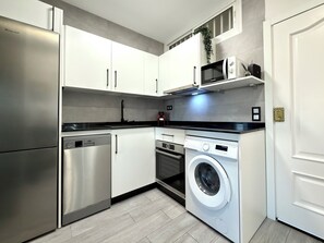 A compact kitchen with a stainless steel refrigerator, a built-in dishwasher, a microwave, and a front-loading washing machine. - Studio with sea views Benalmádena (Benalmádena)