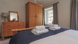 Habitación de hotel con cama, armario de madera, cómoda y ventana con cortinas.