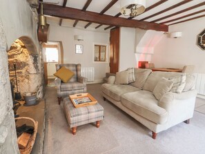 A cozy living room with a fireplace, a sofa, a chair, and a coffee table. - Chamber End Fold (Skipton)