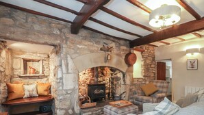 Una sala acogedora con chimenea de piedra, vigas de madera y un espacio de estar confortable.