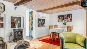 Ein gemütliches Wohnzimmer mit Kamin, Holzbalken und Kunstwerken an den Wänden.