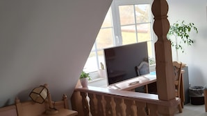 Ett sovrum med en säng, ett skrivbord, en stol, en tv och ett fönster.