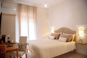 Une chambre d’hôtel bien rangée, avec un lit, des lampes de chevet, un bureau avec une chaise et une fenêtre avec des rideaux.